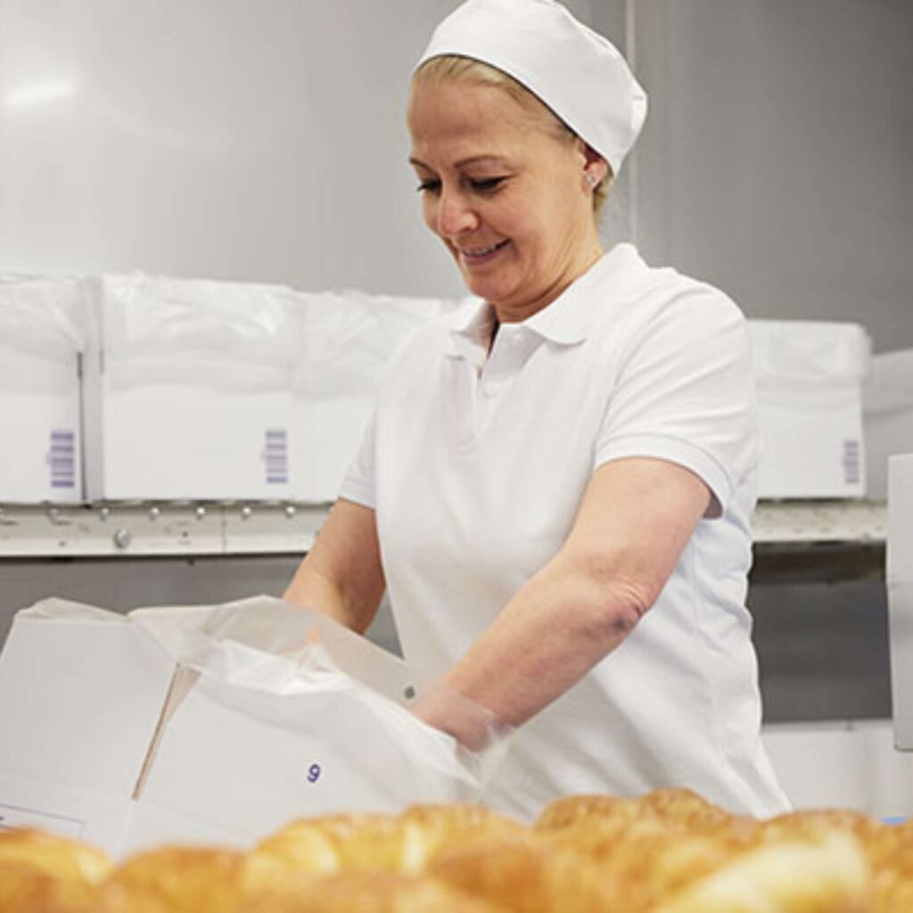 Eine Mitarbeiterin verpackt die tiefgekühlte Backwaren
